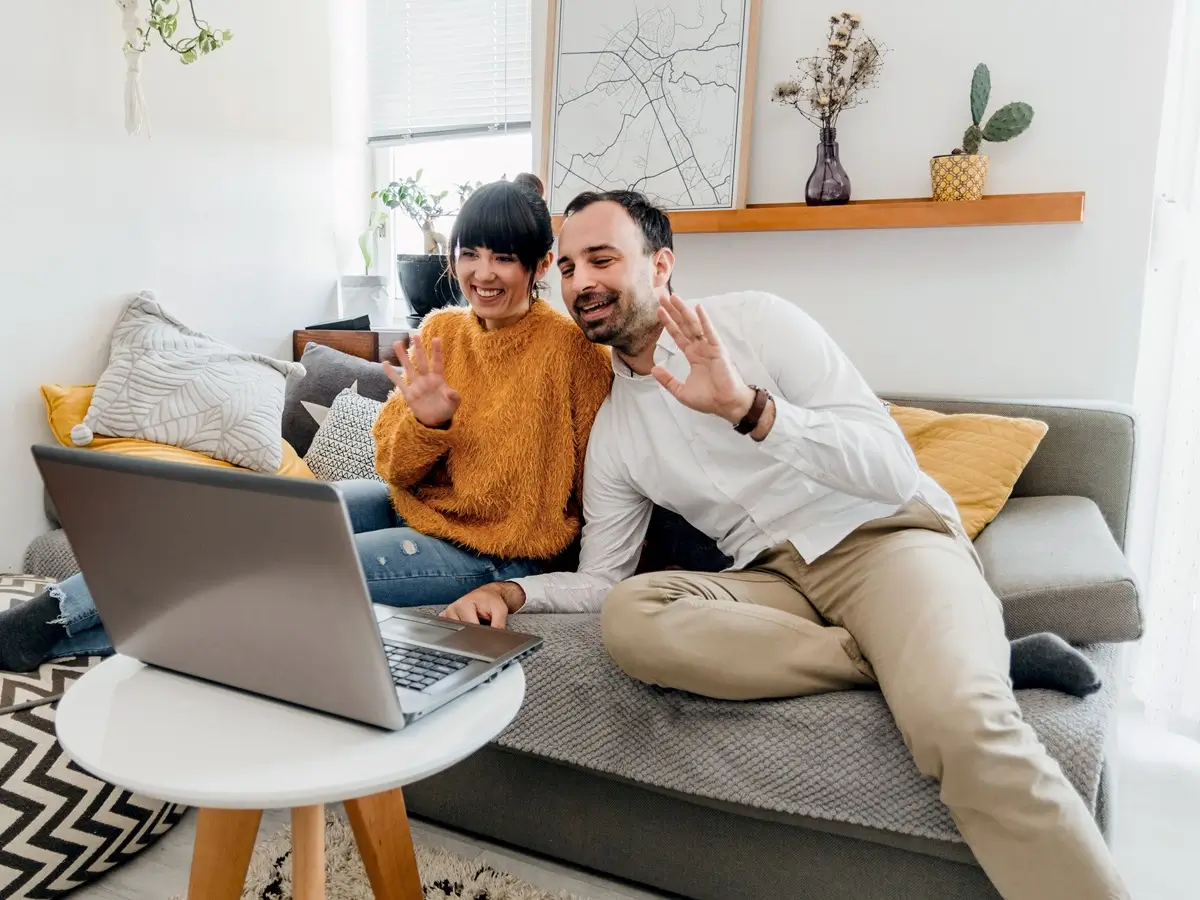 A couple on their sofa joining an online couples therapy session on a laptop